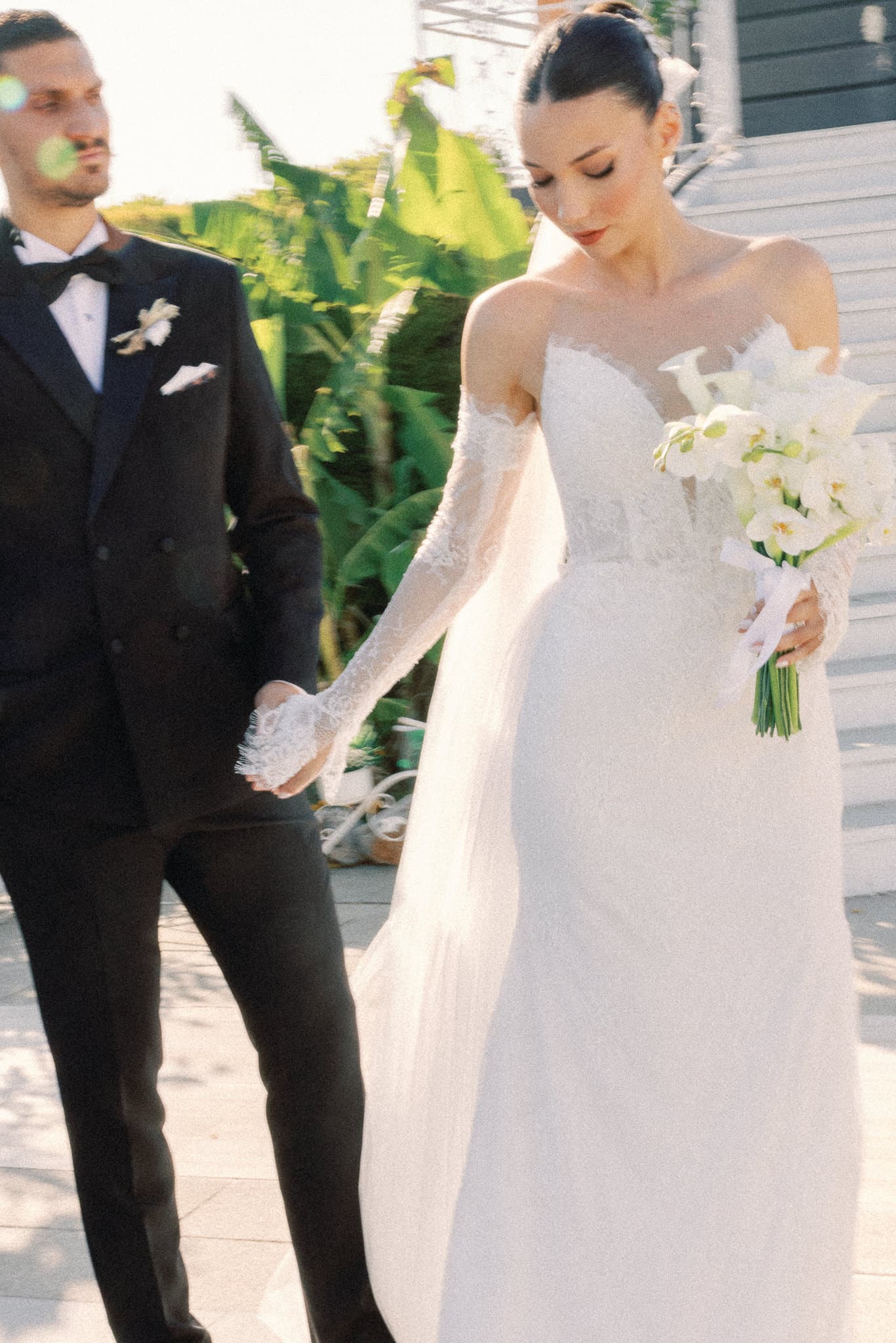 Bahçedeki merdivenlerin önünde el ele yürüyen gelin ve damat